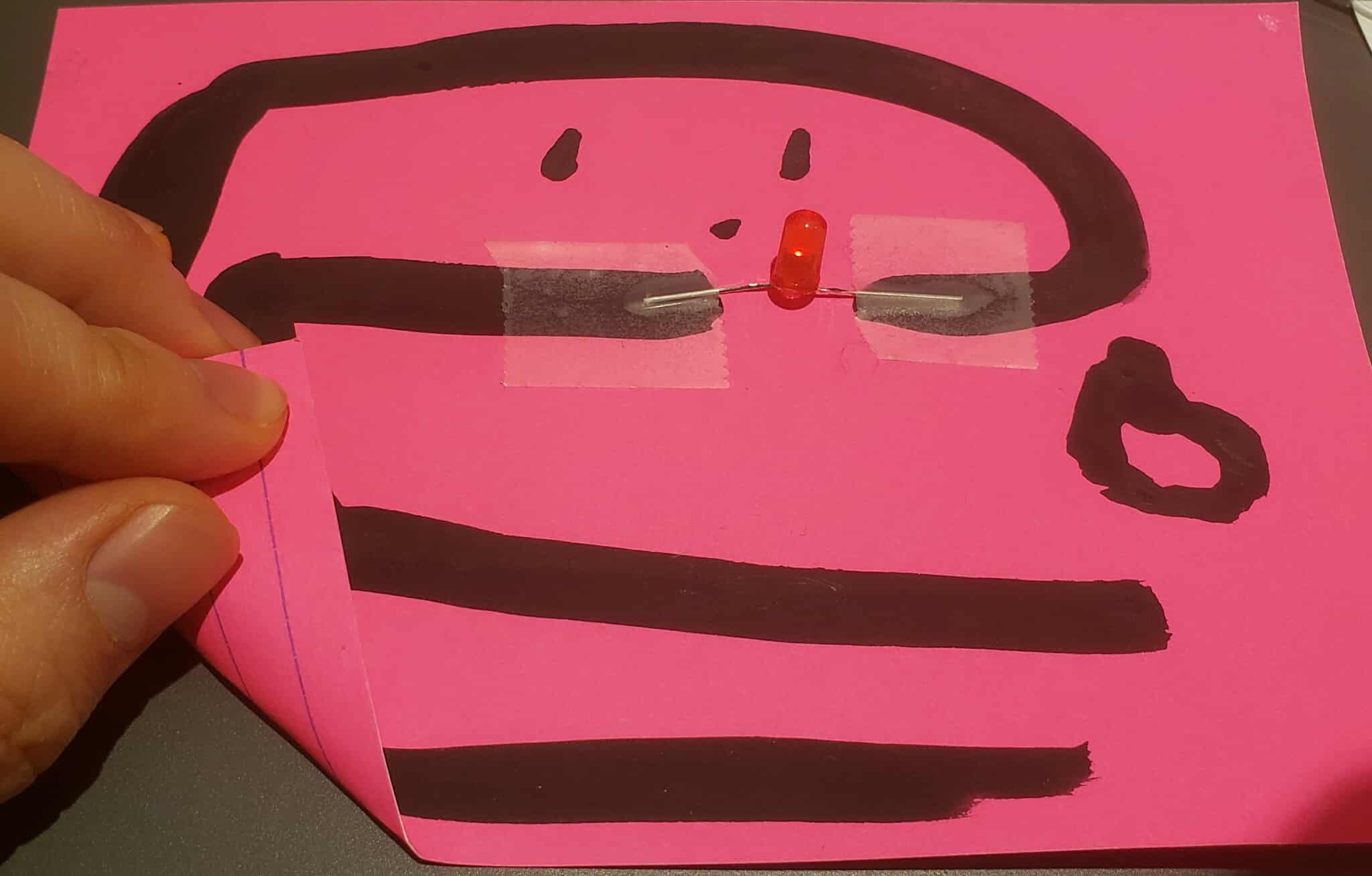 an activated simple circuit using graphite paint. The light is barely visible despite using 2 batteries