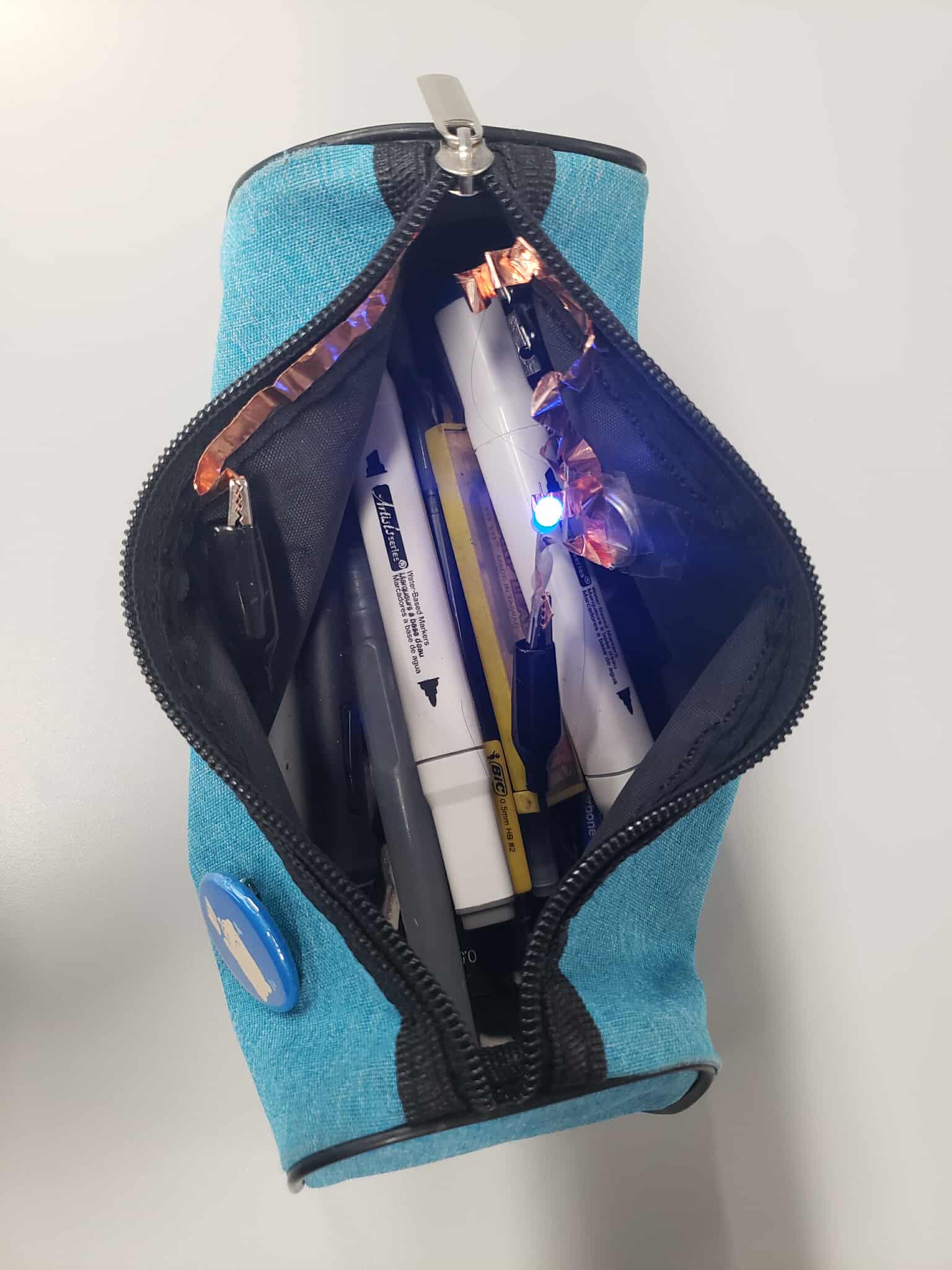 The pencil case with its circuit turned on when the case is opened. A part of the circuit is continuously short circuiting the circuit, preventing the light to be turned on. When the pencil case is opened, that part of the circuit is detached, and the circuit can work normally.