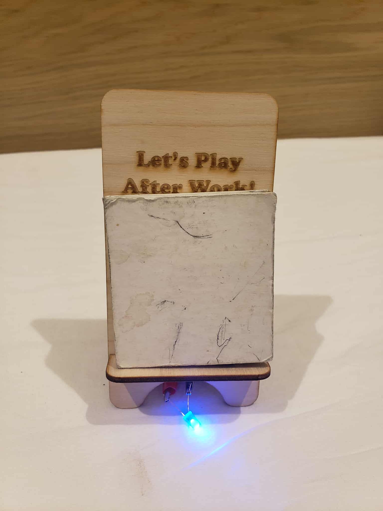 A phone holder with its circuit turned on when a block was placed onto it. There is a switch at the front of the phone holder.